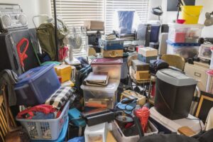 Image of waste in a house, full of boxes, old papers, magazines, clothes etc.